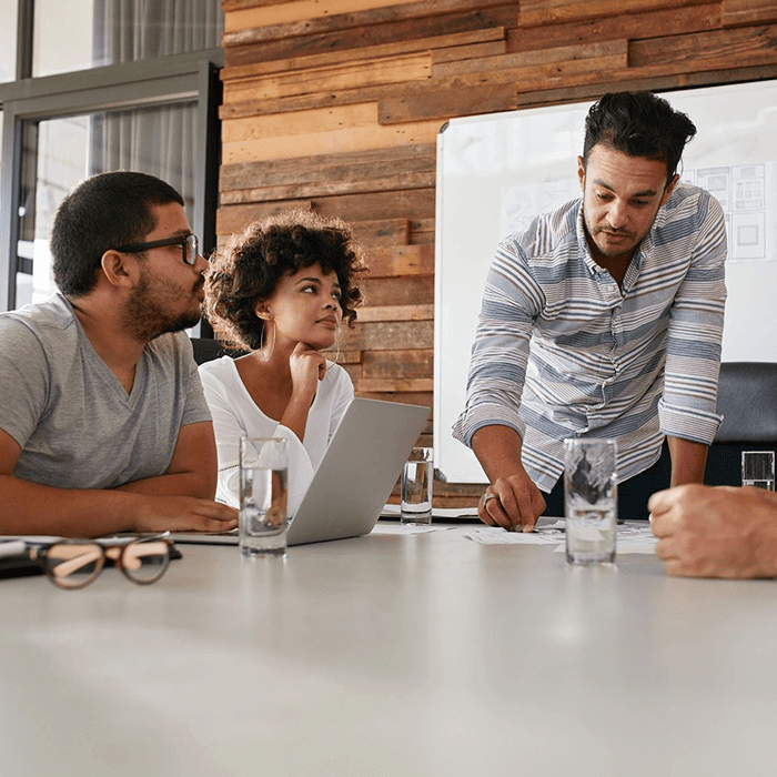 Three people are sitting at a table with a laptop.