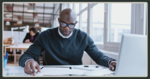 Professional business leader reviewing documents at desk in modern office, focused on strategy, decision-making, and leadership productivity